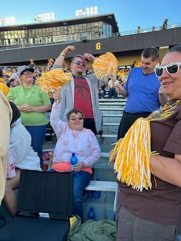 A Group of People are Sitting in a Stadium Holding Pom Poms — Cheyenne, WY — Treasure Abilities