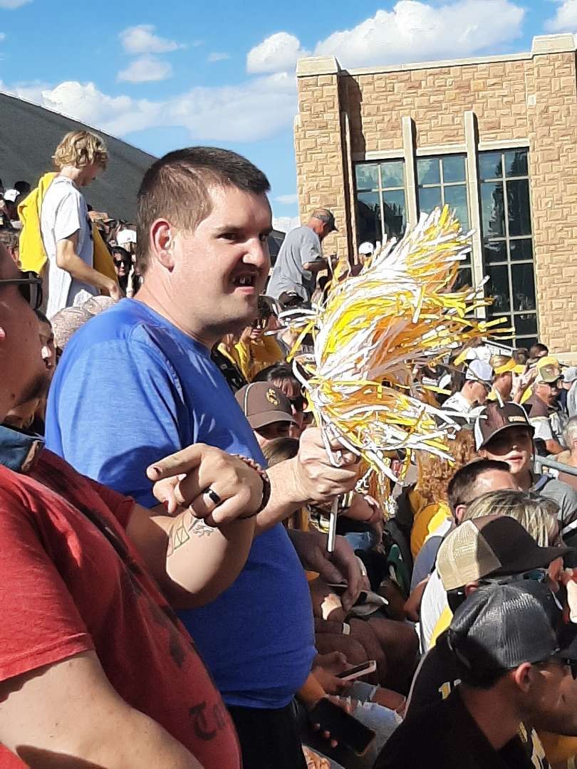 A Man Wearing a Blue Shirt Holding a Pom Pom — Cheyenne, WY — Treasure Abilities