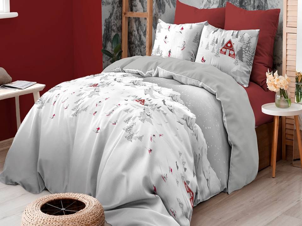 Un letto con un piumone bianco e cuscini rossi in una camera da letto.