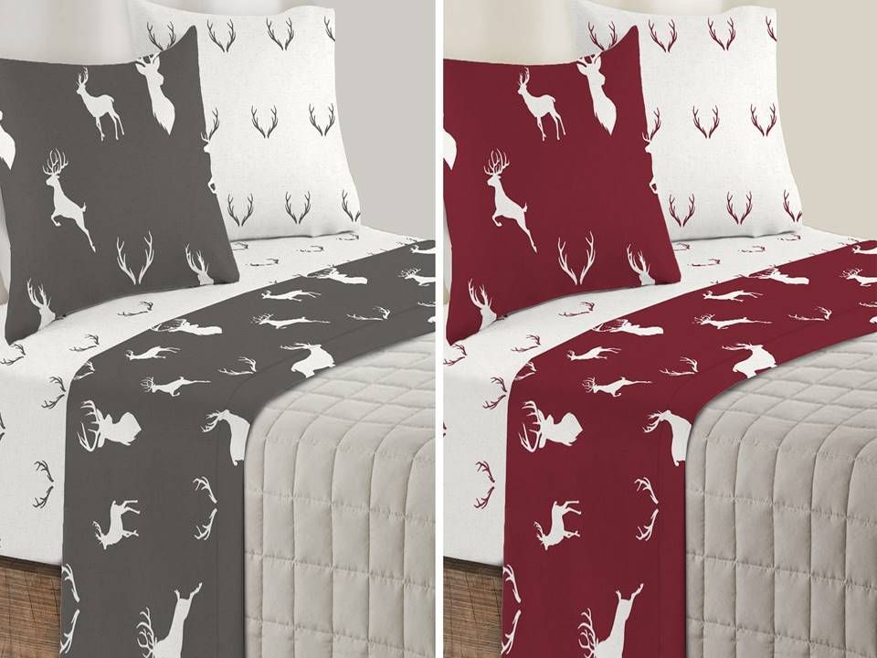 Un letto con due cuscini e una coperta con un cervo sopra