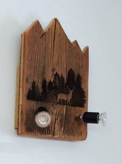 Una targa di legno con un cervo e degli alberi sopra