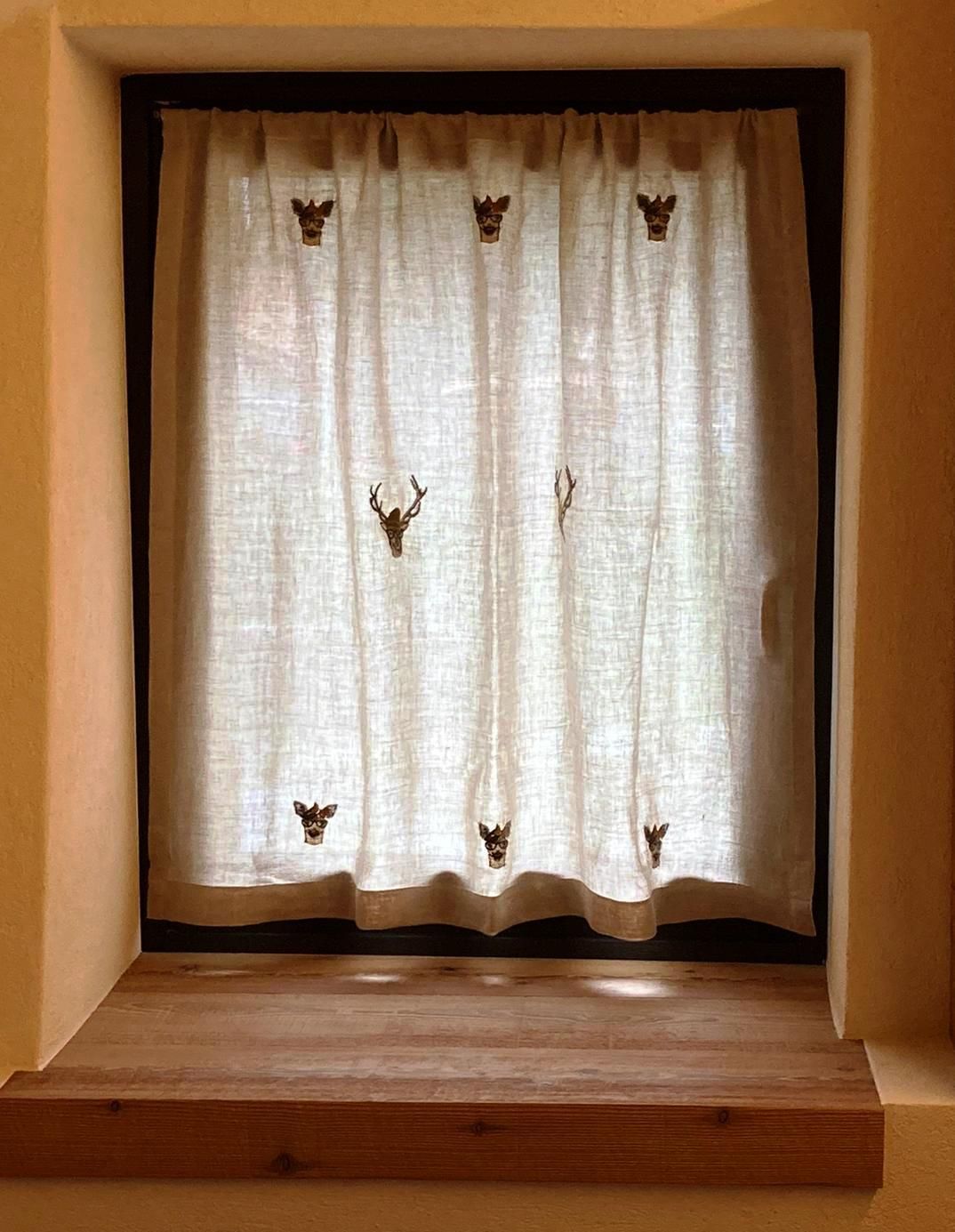 Una finestra con una tenda e un davanzale di legno.