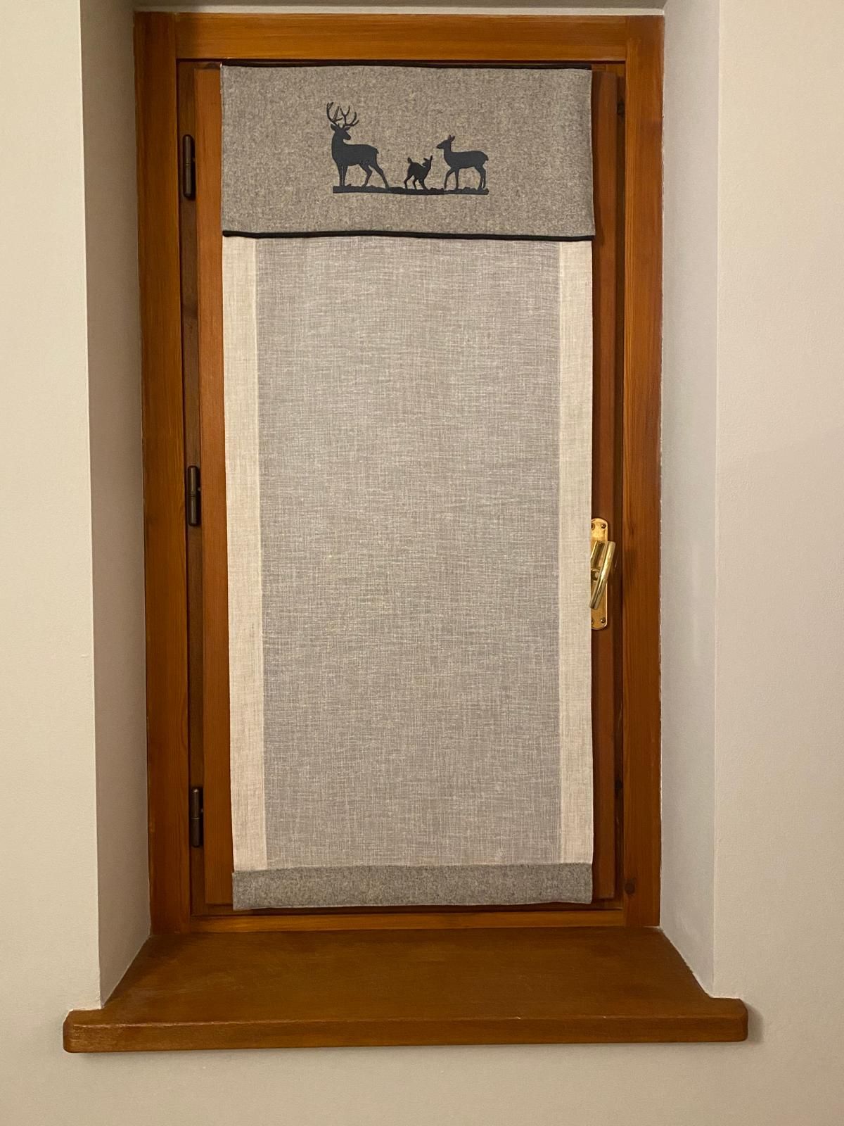 Una finestra con una tenda e un cervo ricamato sopra.