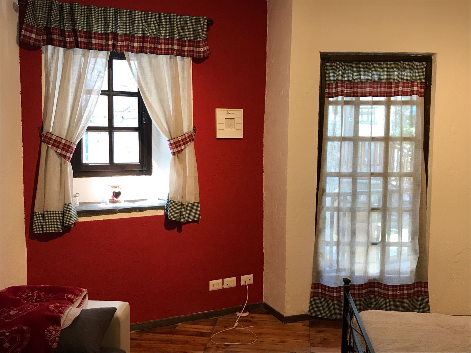 Una camera da letto con una parete rossa e tende bianche