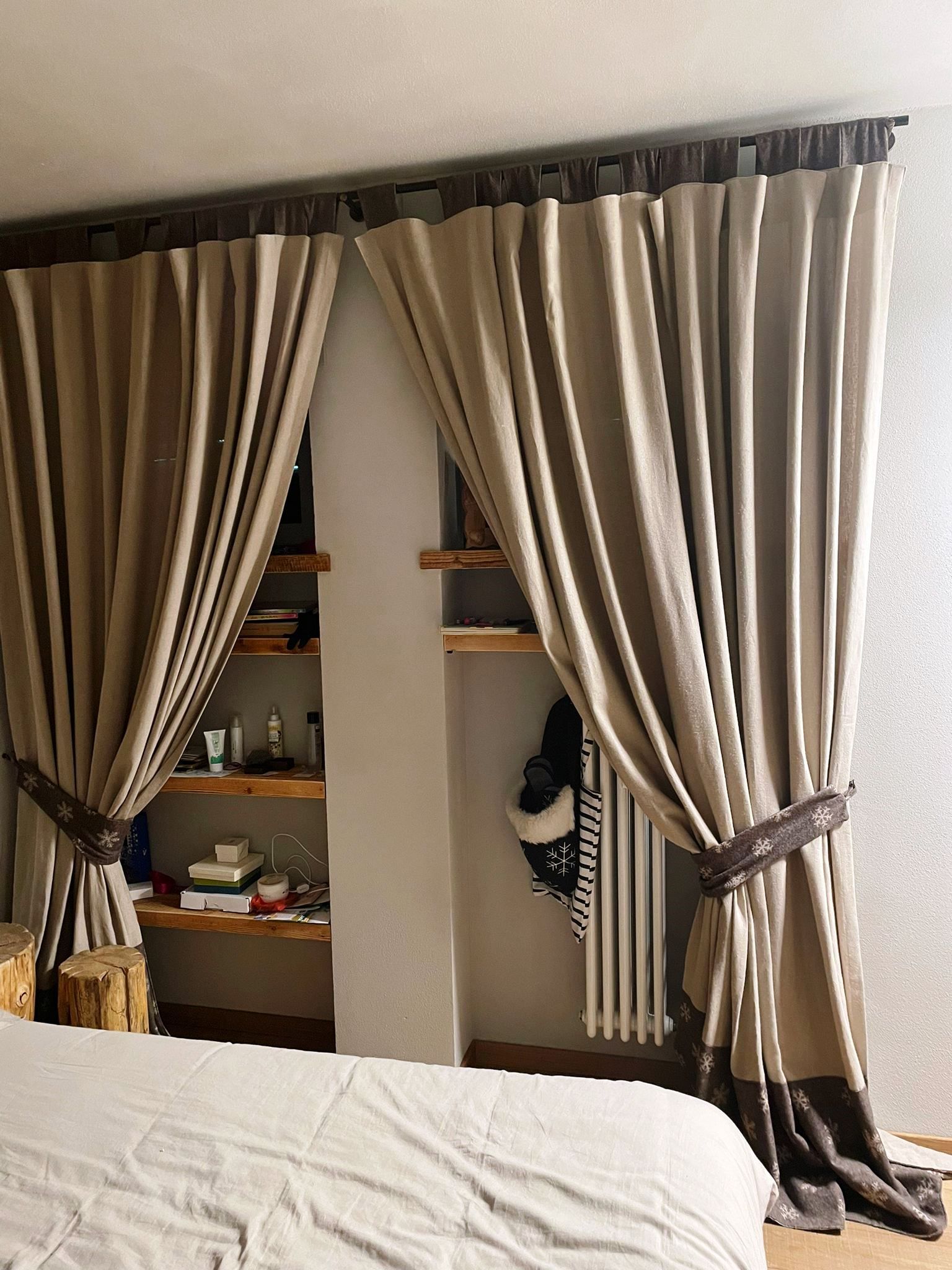 Una camera da letto con un letto, scaffali, tende e un termosifone.