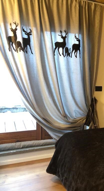 Una camera da letto con un letto e delle tende con dei cervi sopra