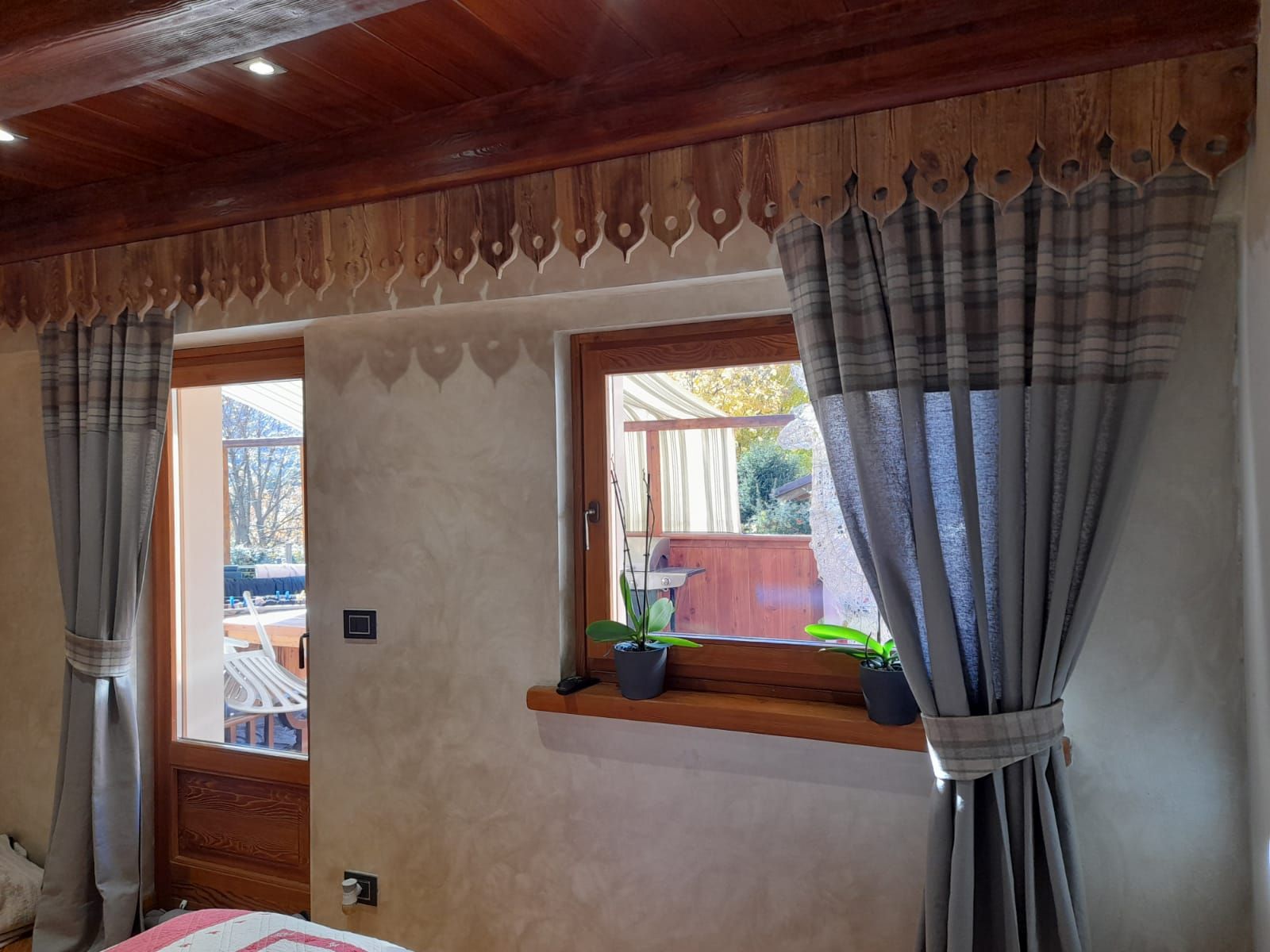 Una camera da letto con un letto, tende, una finestra e un soffitto in legno.