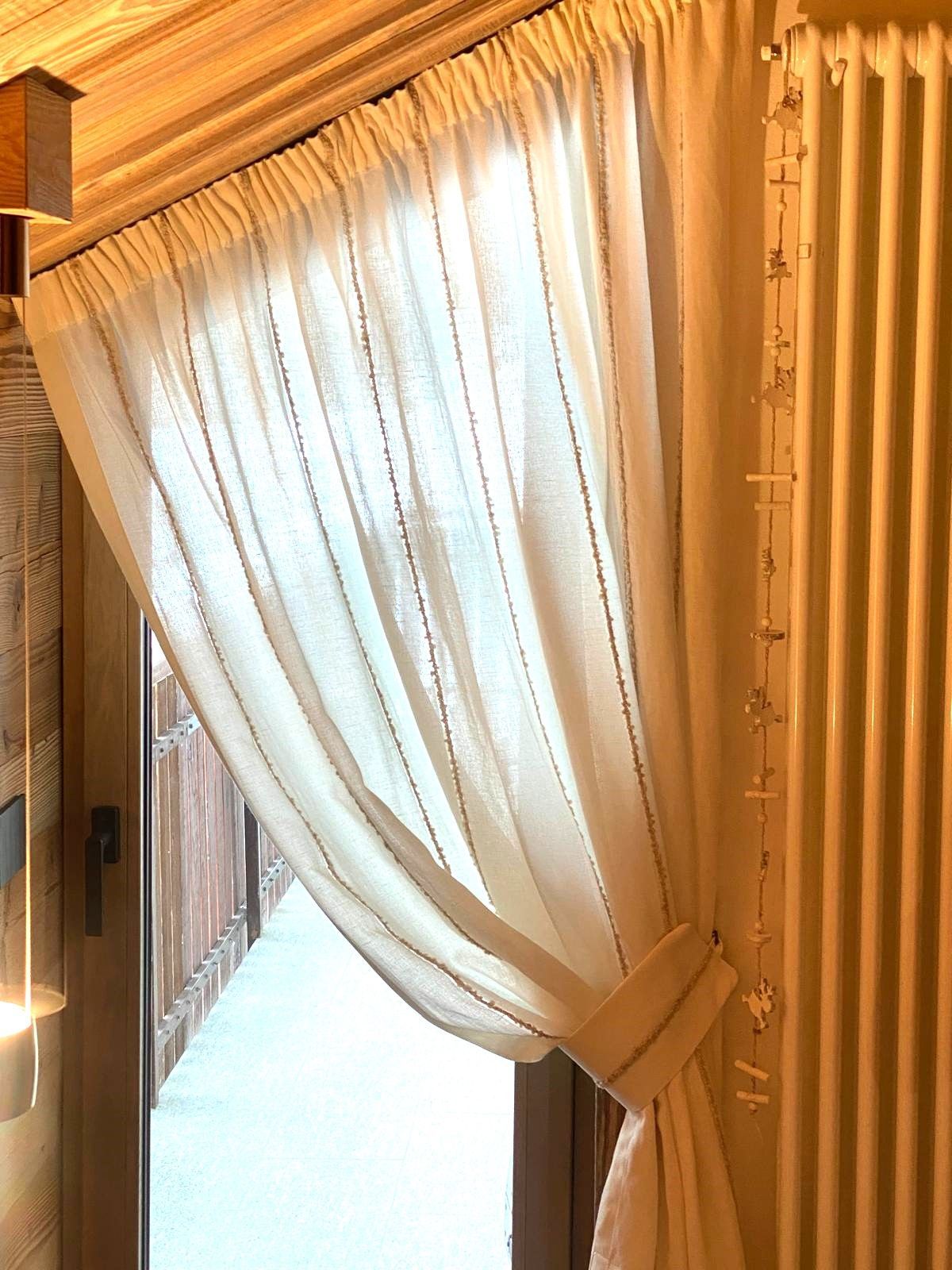 Una tenda bianca è appesa a una finestra accanto a una porta.