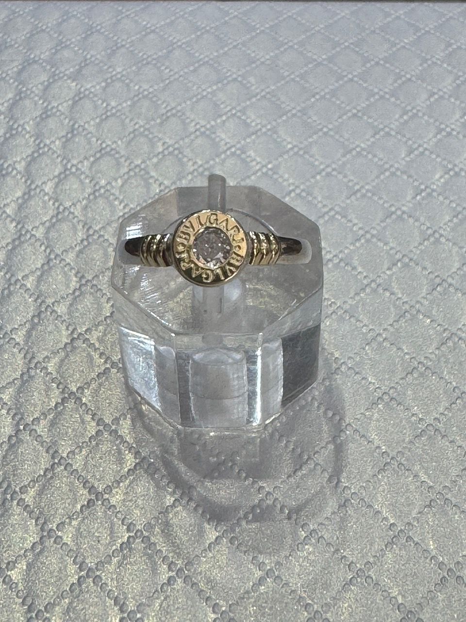 Anillo con piedra central transparente, engastada en una banda de metal amarillo
