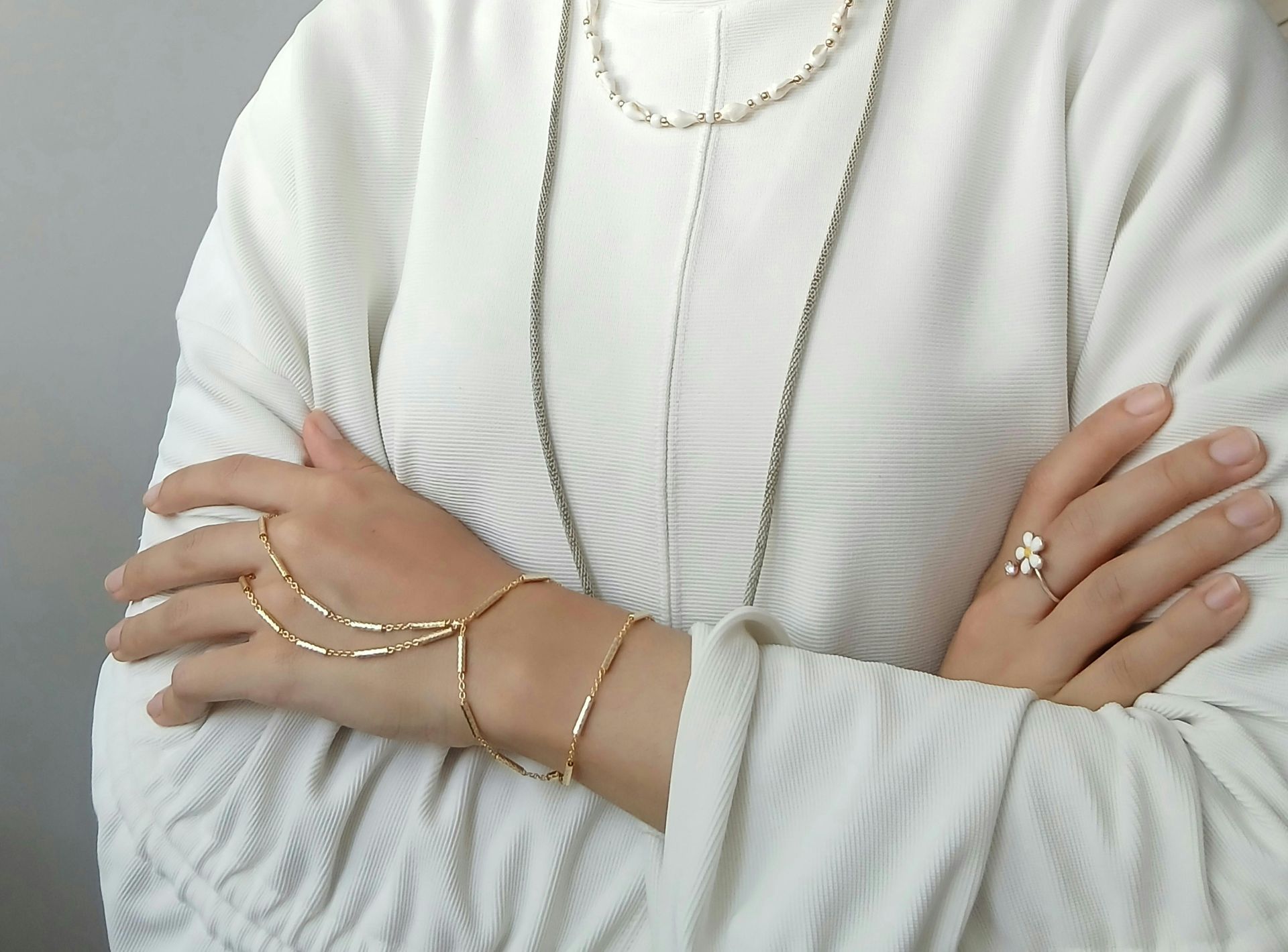 Una mujer que lleva pulseras y un anillo con los brazos cruzados.