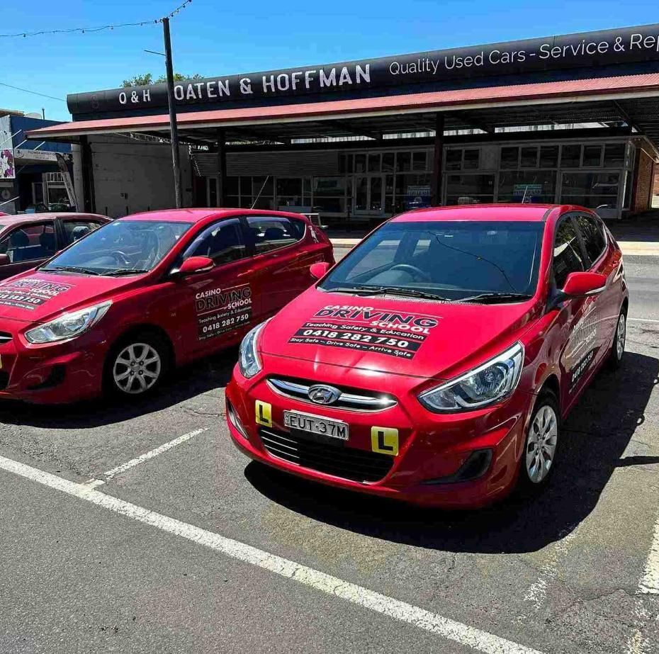 Two Red Cars Are Parked in a Parking Lot in Front of a Building — Casino Driving School In Kyogle, NSW