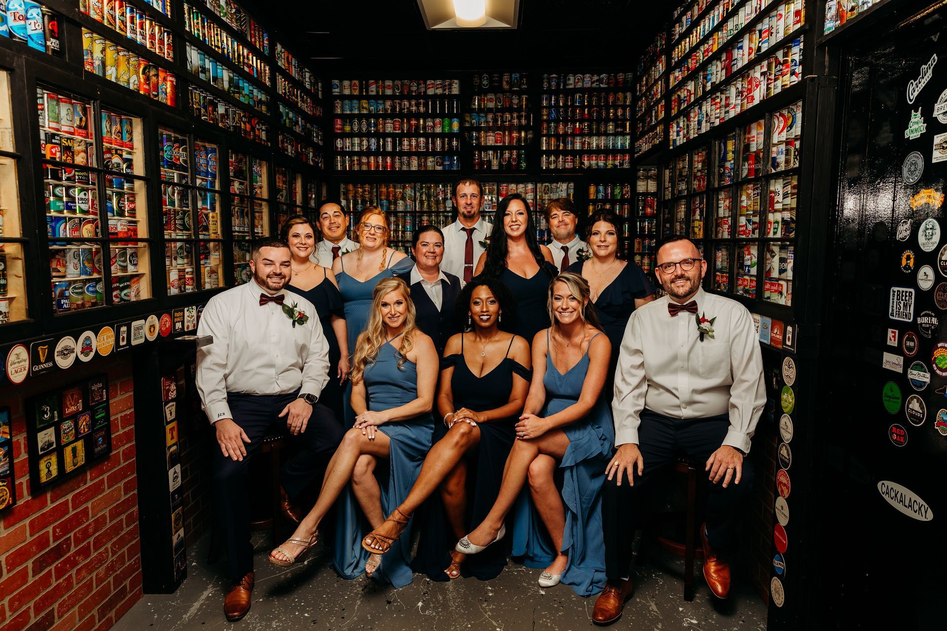 Wedding party poses in a room lined with shelves of cans. Formal attire, smiling.