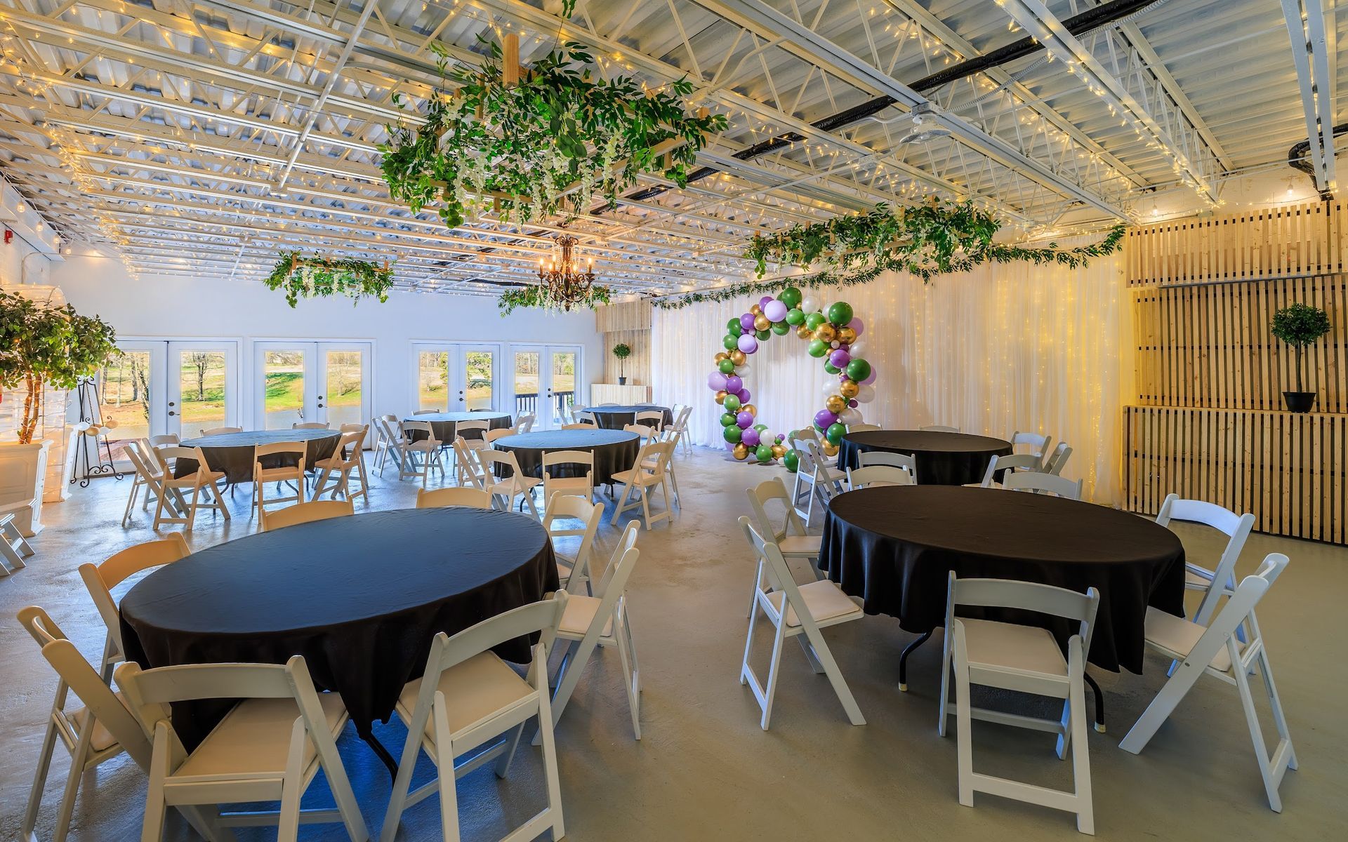 Event space with round tables, white chairs, and floral decorations.