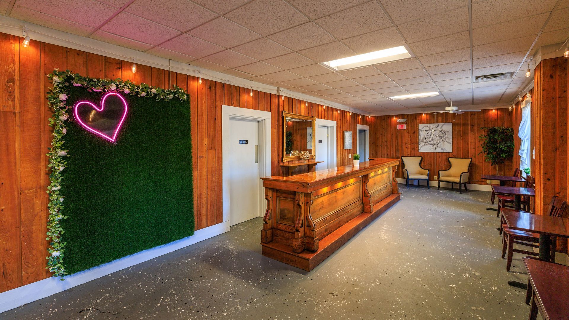 Interior with wood paneling, bar, heart neon sign, and seating.