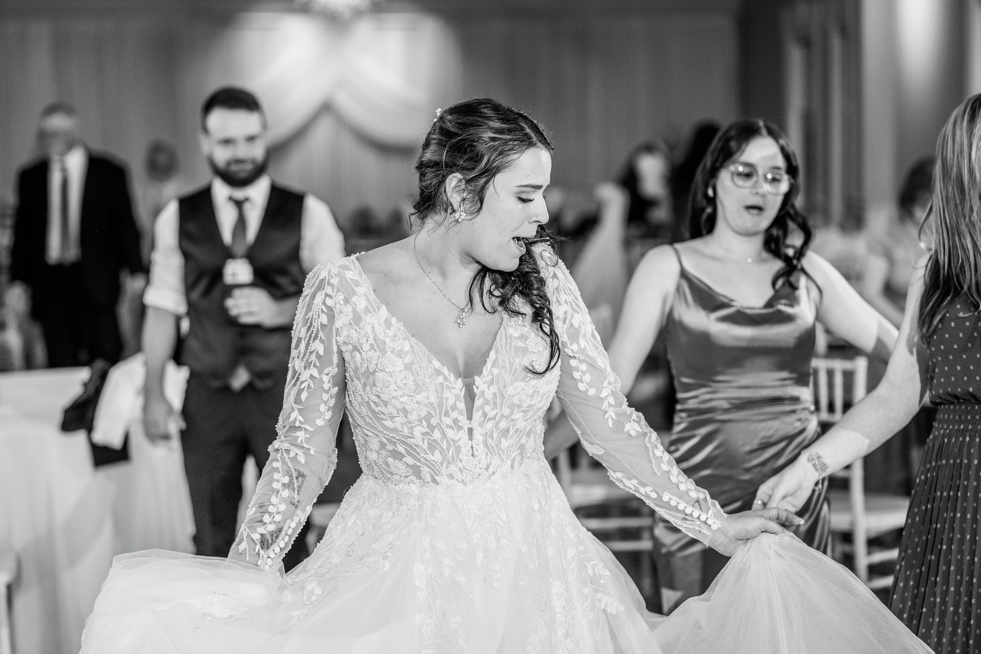 Bride in wedding dress dancing with guests at reception.