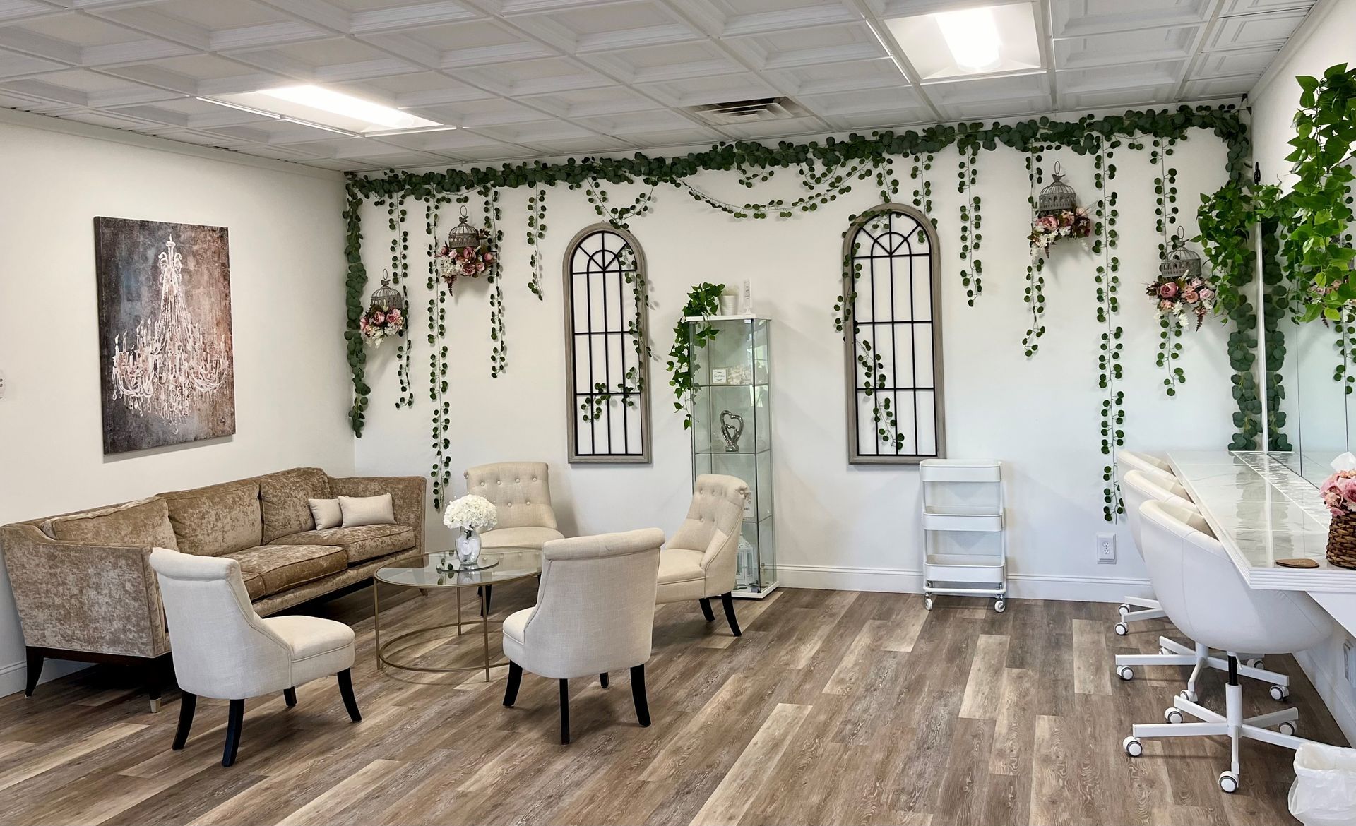 Interior waiting room, floral decorations, seating area with couches, chairs, and tables. Light wood flooring.