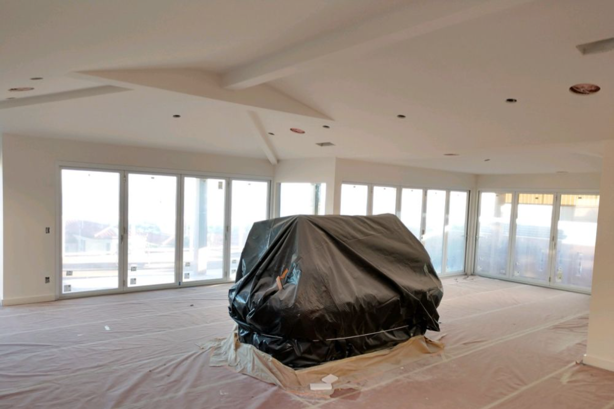 An empty room with a couch covered in plastic