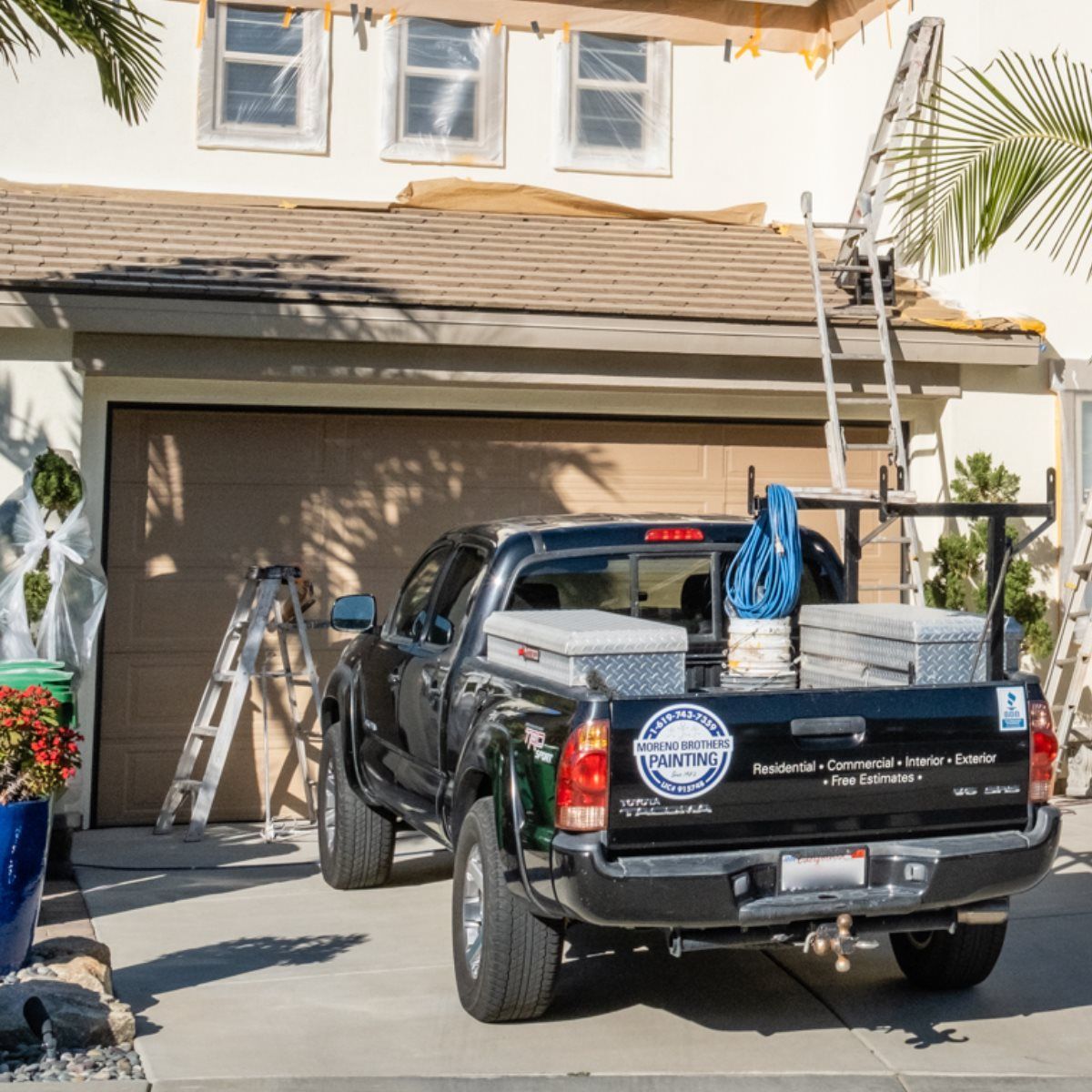 A truck is parked in front of a house that is being painted.