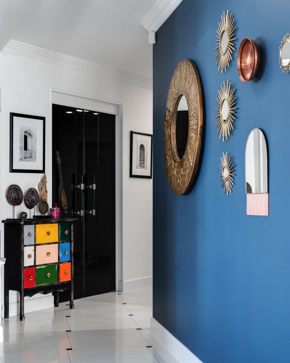 A hallway with a blue wall and a colorful dresser