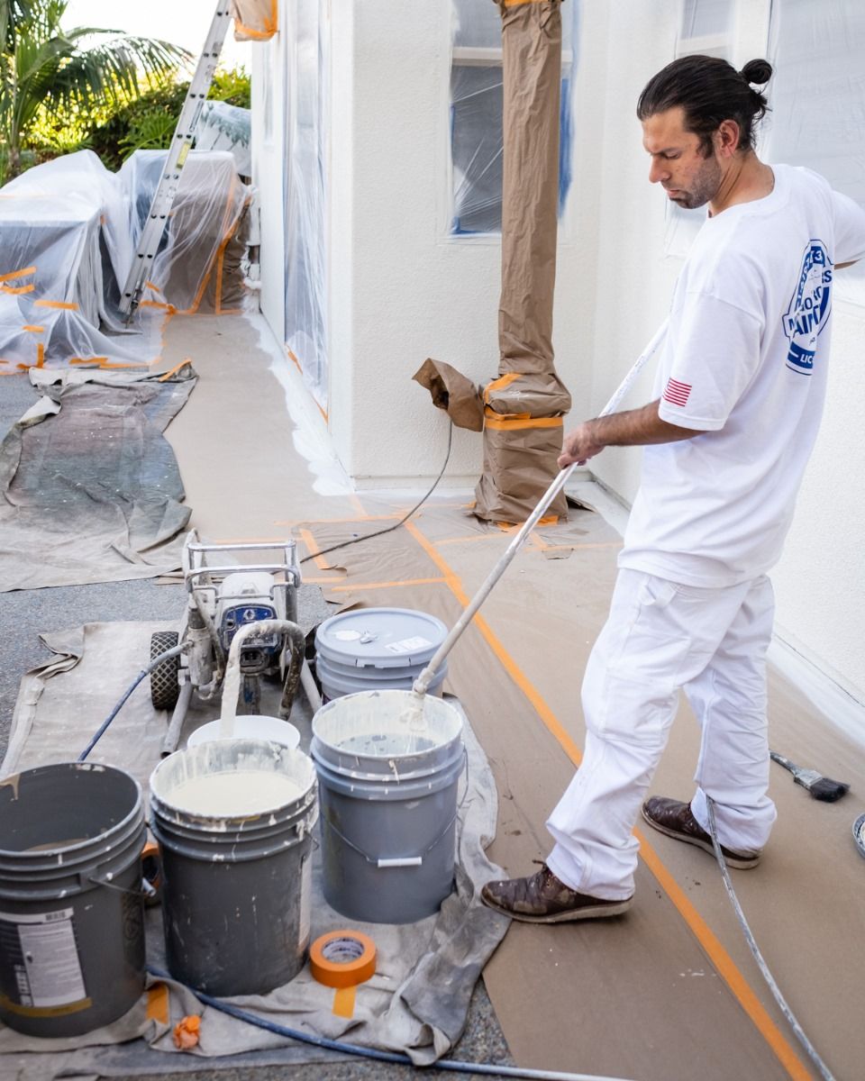 A man is standing in front of buckets of paint