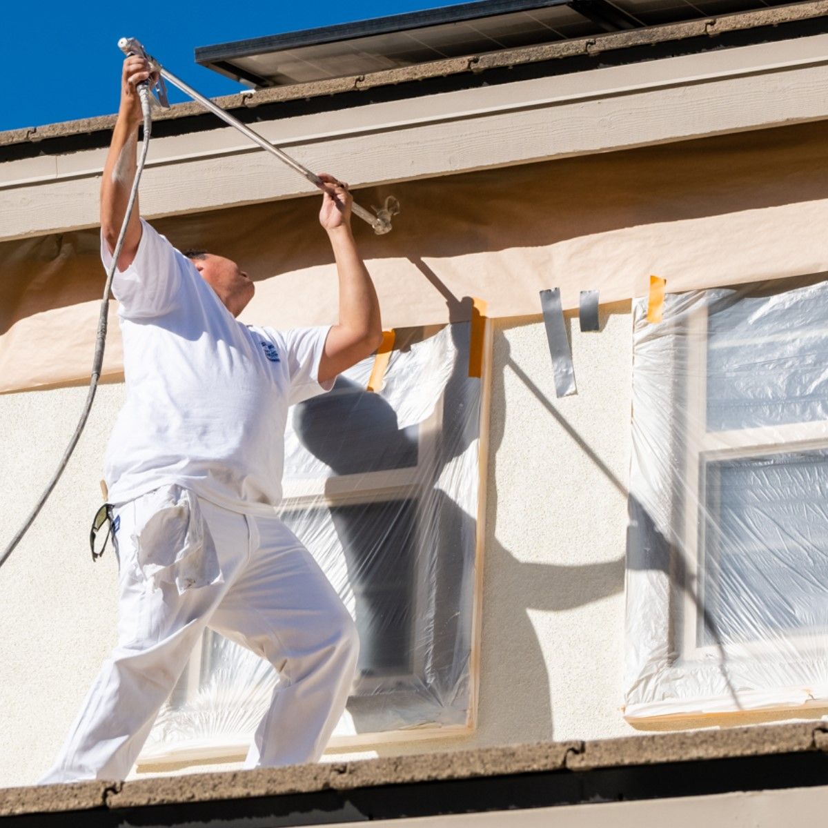A man is painting the side of a building with a hose