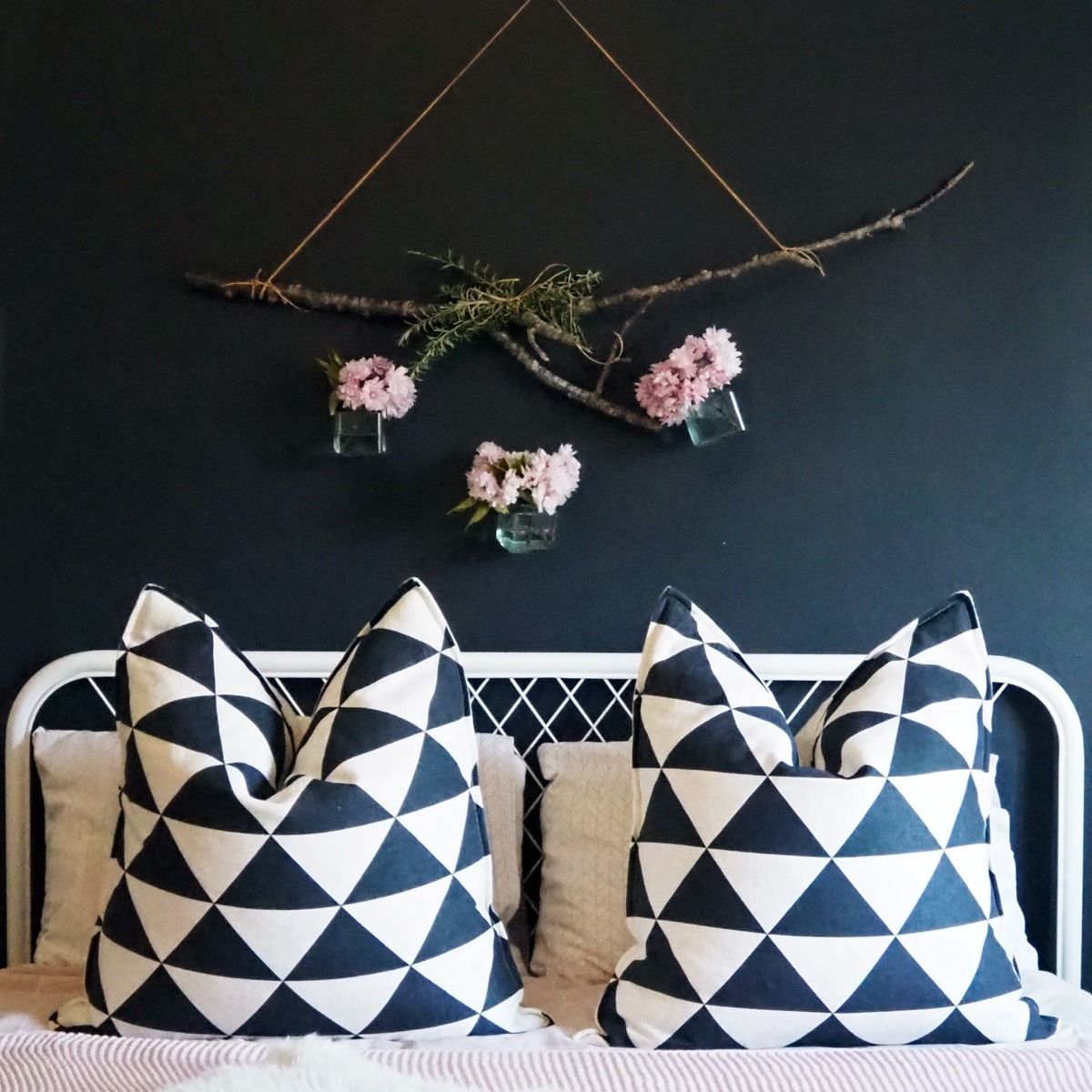 A bed with black and white pillows and a black wall