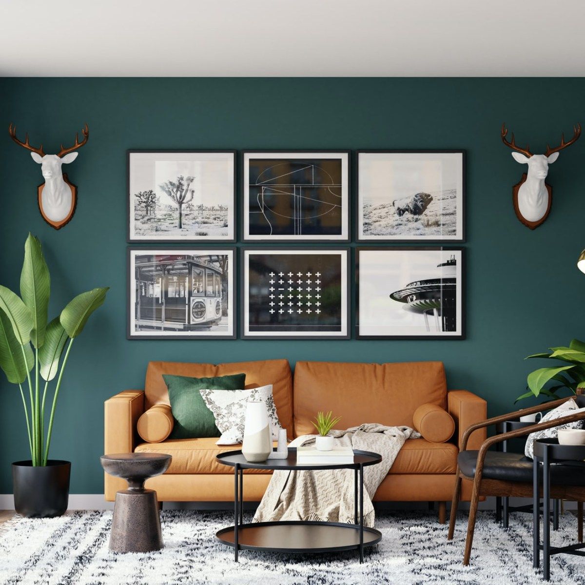 A living room with a couch , coffee table , chairs , plants , and deer antlers on the wall.