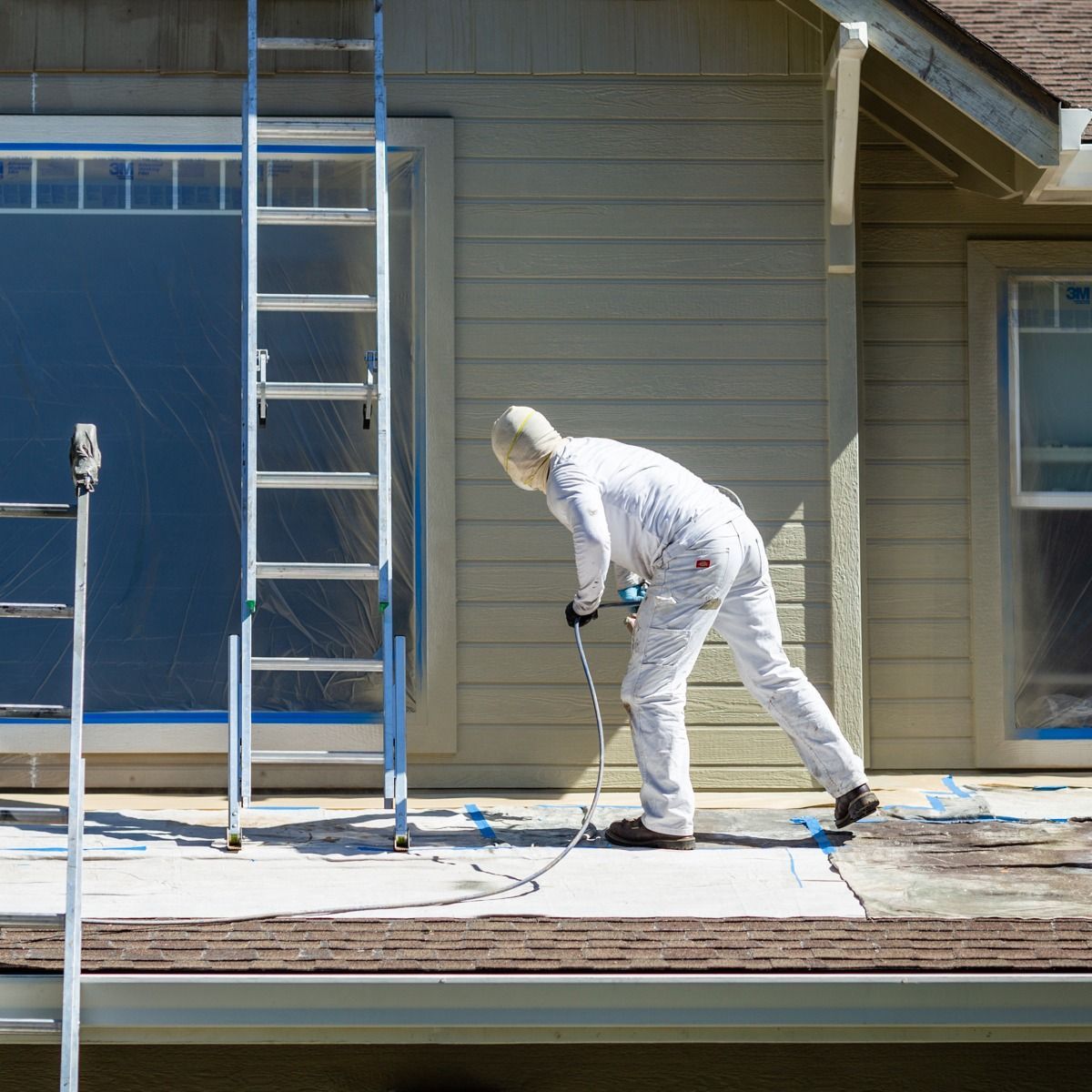 A man is painting the side of a house