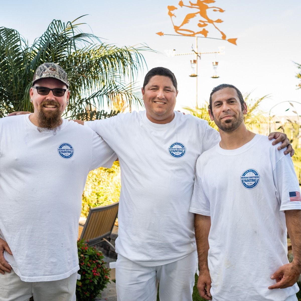 Three men in white shirts are posing for a picture