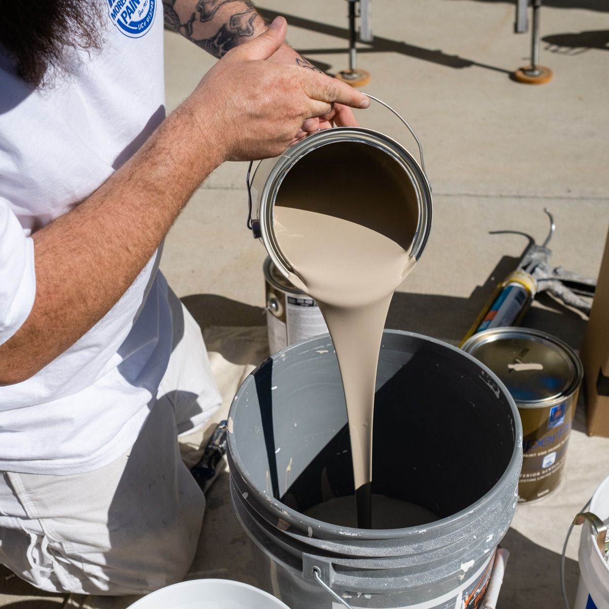 A man pouring paint from a can into a bucket