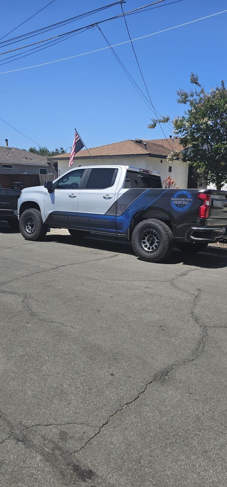 A white truck is parked on the side of the road in front of a house.