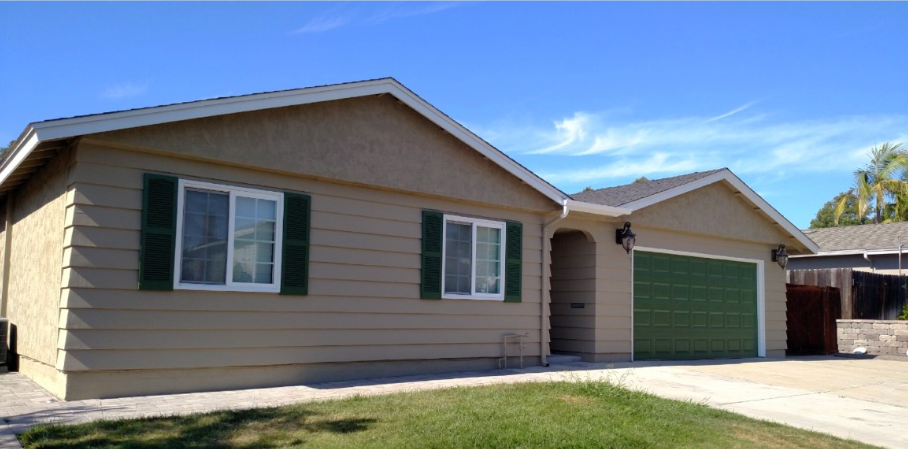 A house with green garage doors and shutters on the windows