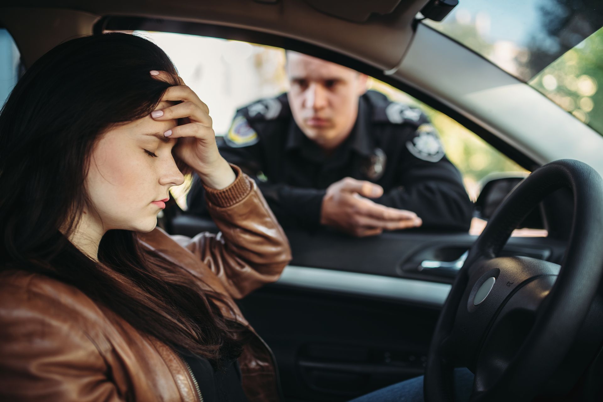 A woman is sitting in a car talking to a police officer