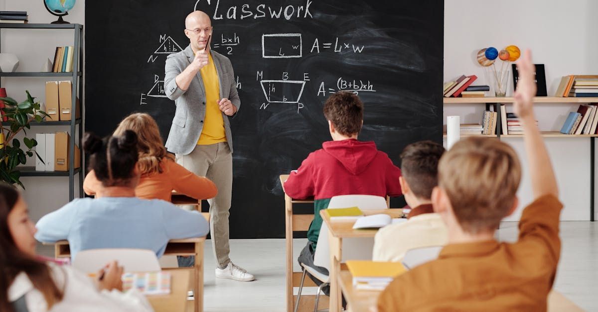 Teacher standing in front of a class of children, with a blackboard behind him