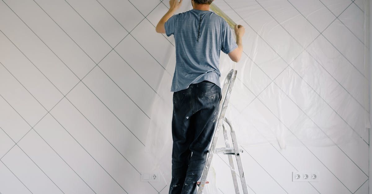 Man on a ladder painting a wall inside a house
