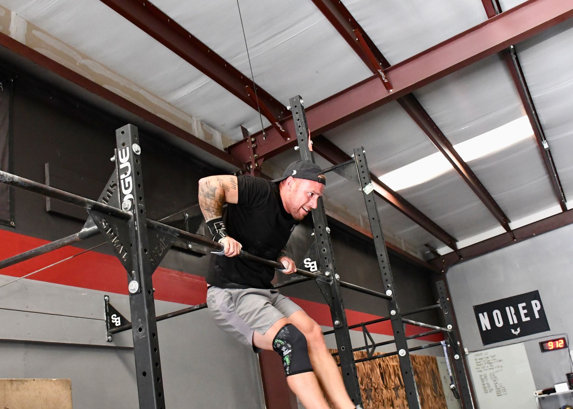 People stretching at a gym, bending forward while holding onto a vertical bar.