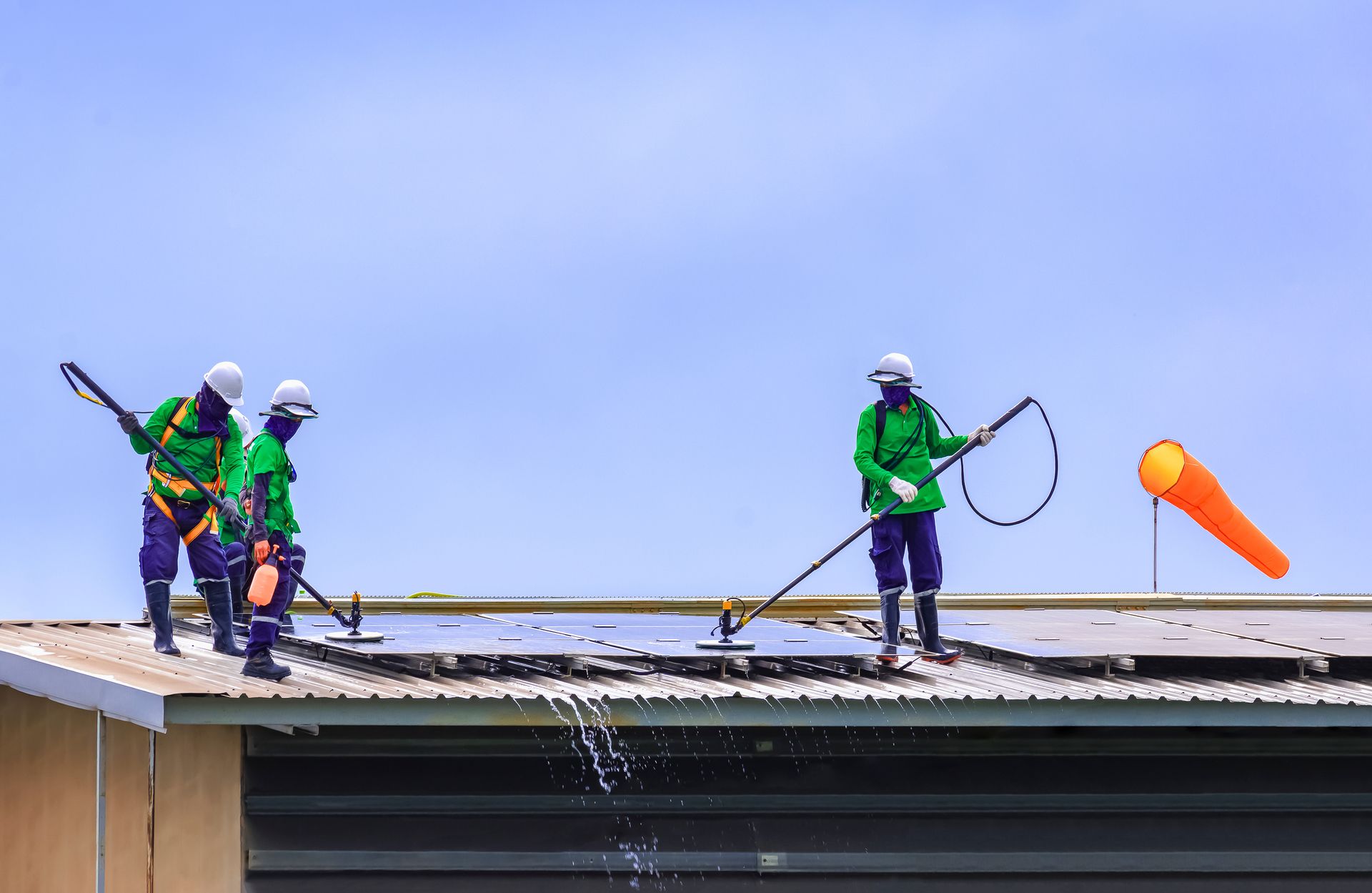 Workers on a rooftop using safety lines, with one launching an orange tool into the air.