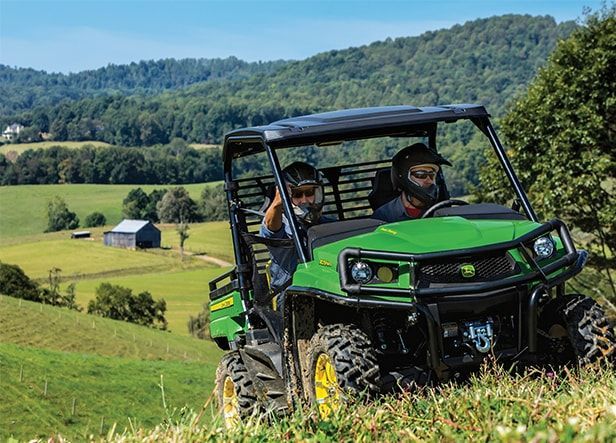 A man is driving a green John Deere tractor