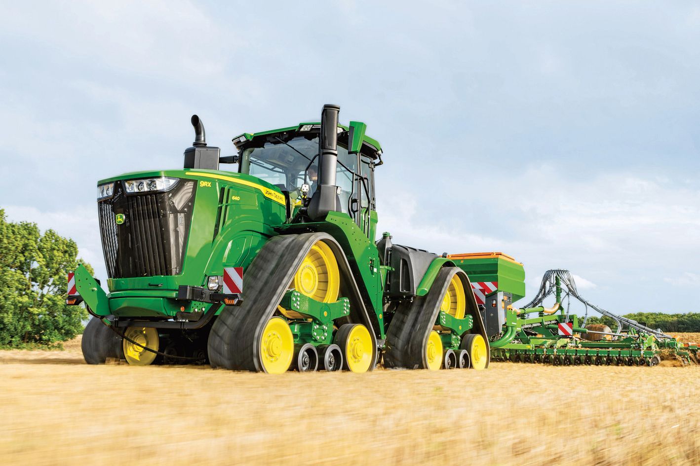 A man is riding a John Deere lawn mower on a lush green lawn.