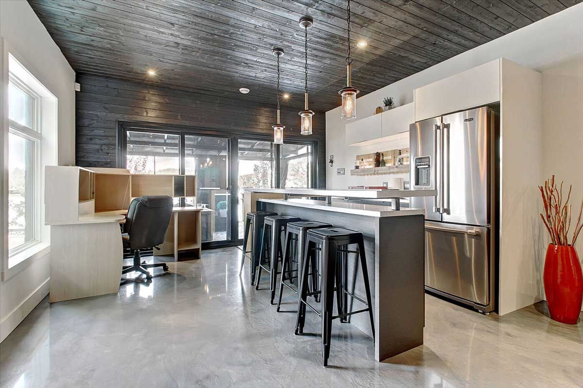 Cuisine moderne avec un îlot gris, des tabourets noirs et des appareils électroménagers en acier inoxydable.