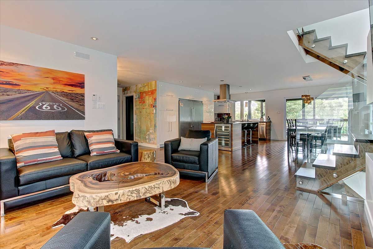 Espace de vie ouvert comprenant salon, cuisine et salle à manger. Parquet, meubles en cuir et œuvres d'art.