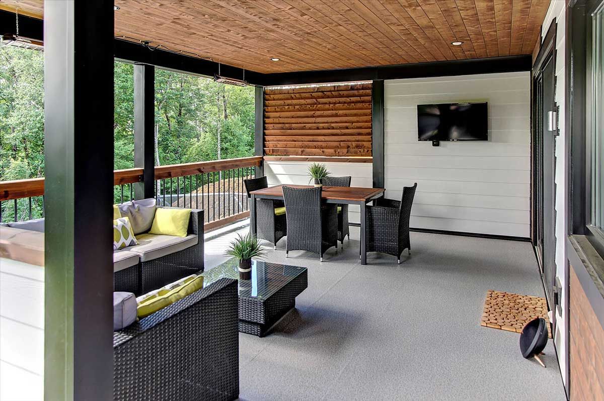 Terrasse extérieure avec sièges, table à manger, télévision et plafond en bois.