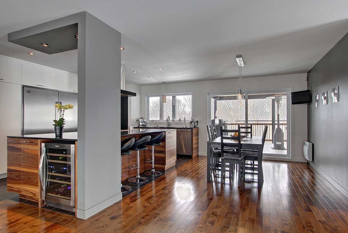 Cuisine et salle à manger modernes avec parquet, appareils électroménagers en acier inoxydable et touches de couleurs sombres.