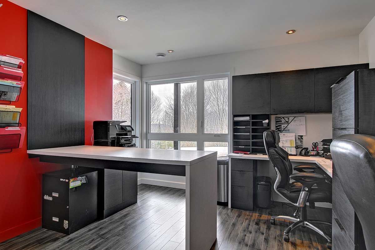 Bureau à domicile moderne avec des touches de rouge et de noir, un bureau et une grande fenêtre.