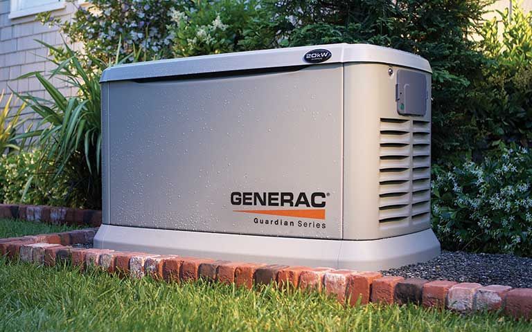 A generac generator is sitting in the grass in front of a house.