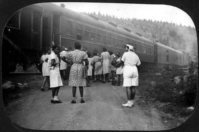 A black and white photo of people standing in front of a train