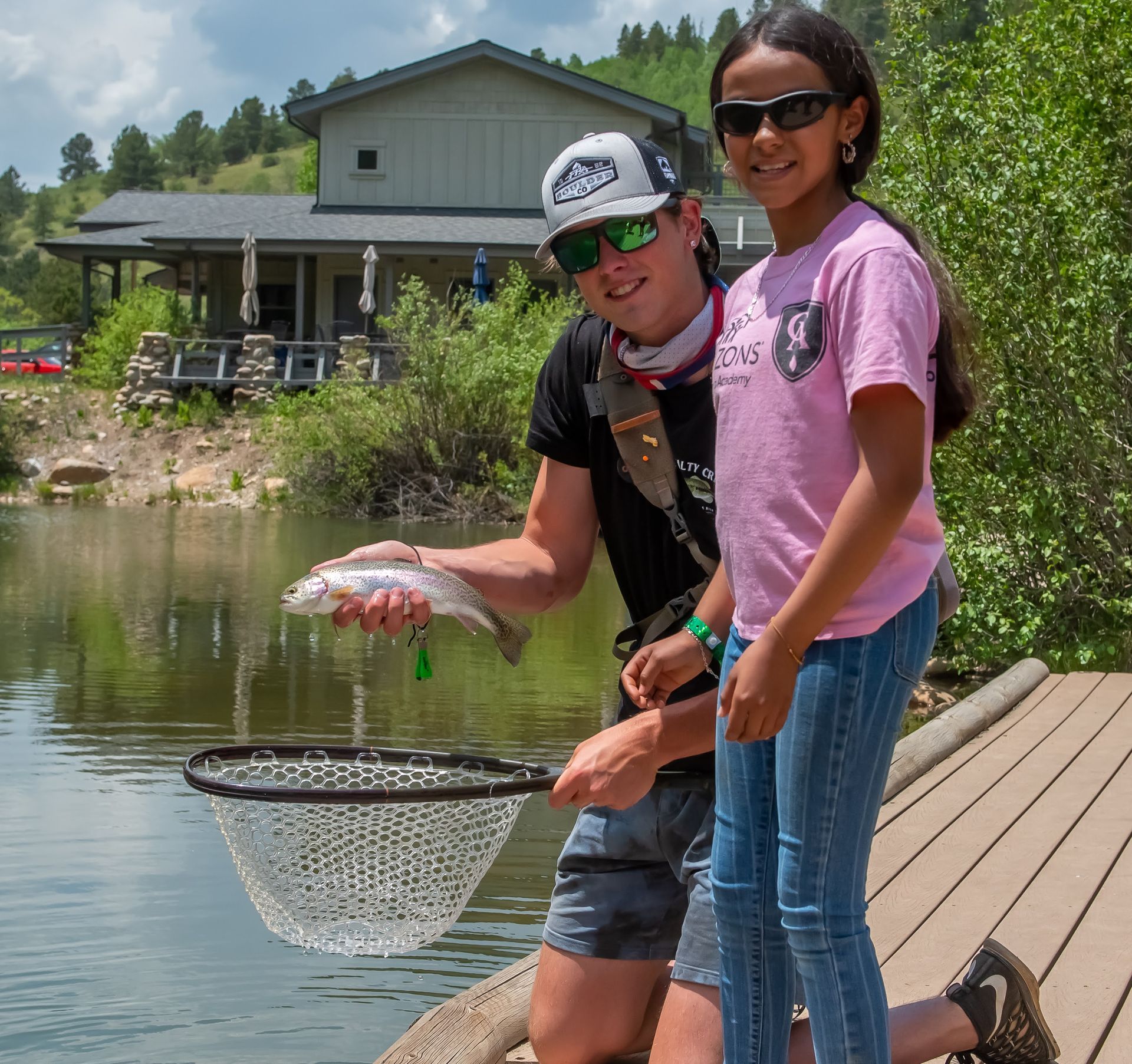 A man and a girl are standing on a dock holding a fish