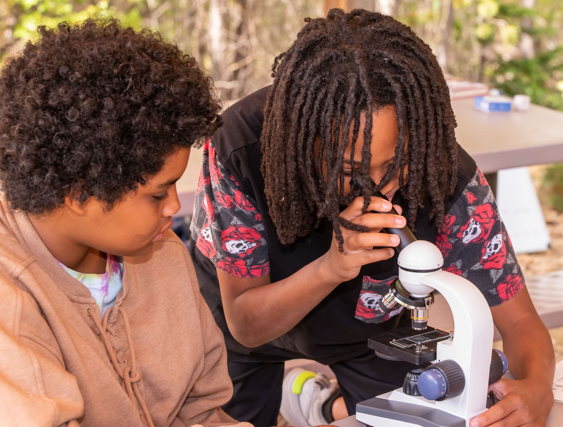 Two young boys are looking through a microscope.