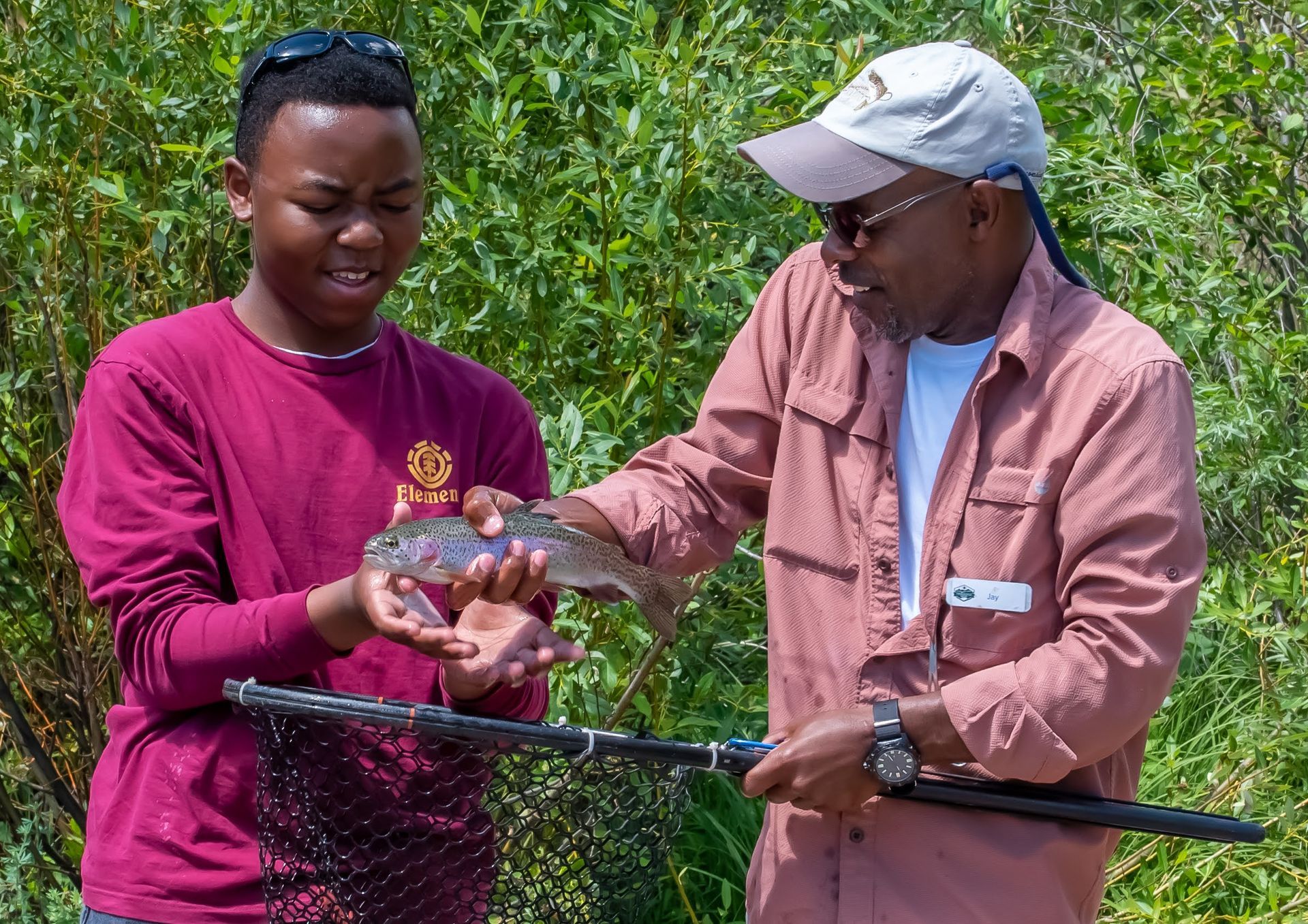 A man and a boy are holding a fish in their hands.