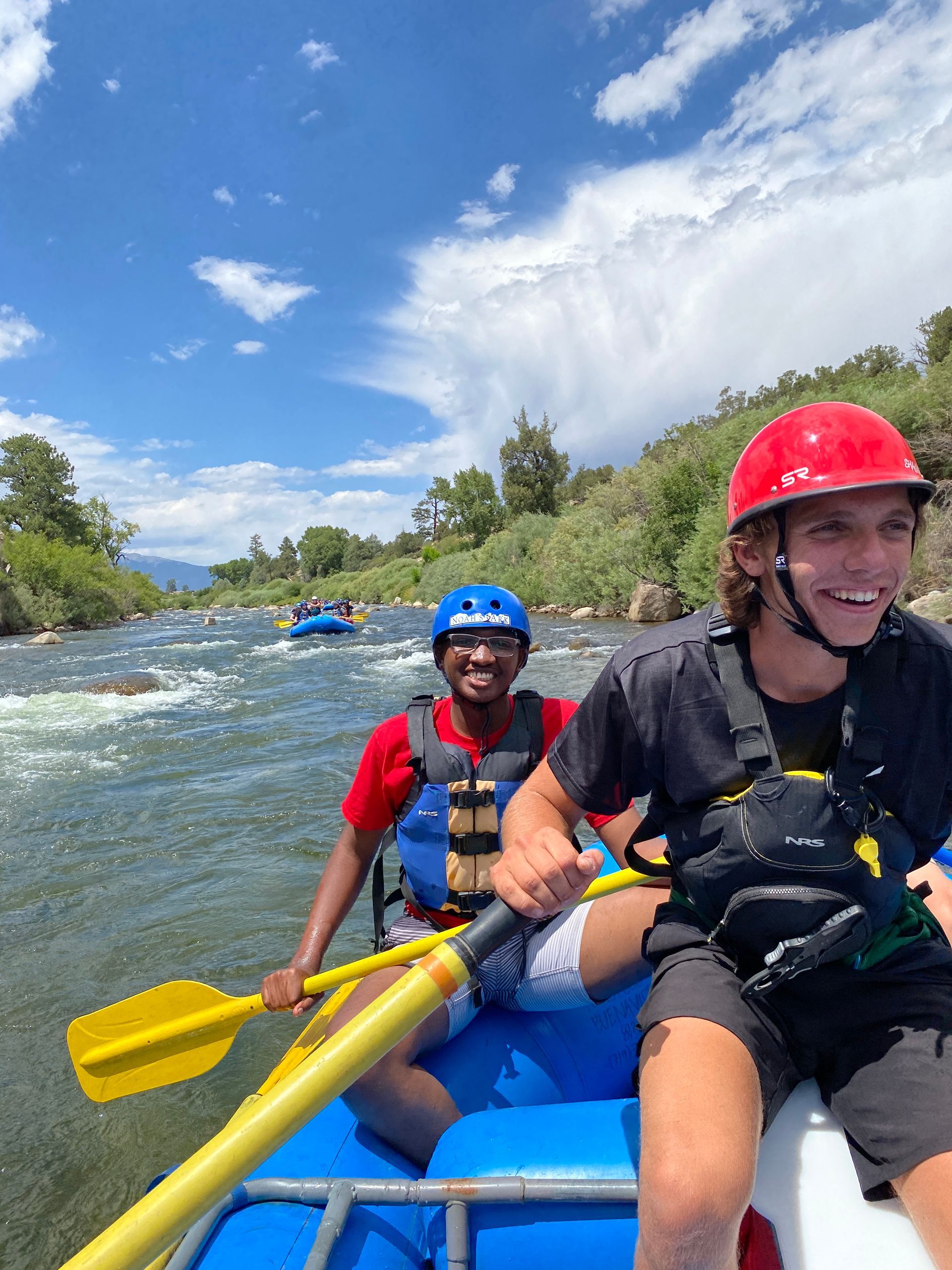 Two men are rowing a raft down a river.